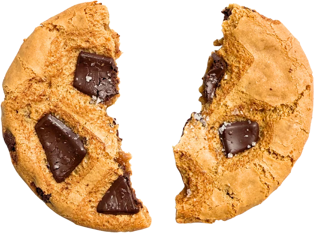 A chocolate chip cookie broken in half, showing the chocolate chunks inside.