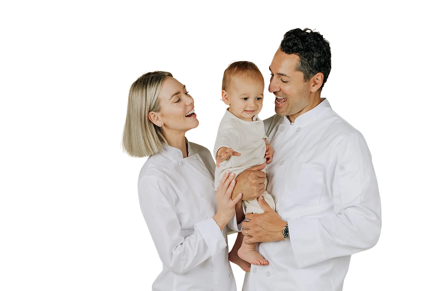 The two founders of Nowhere Bakery in white chef coats, laughing with their baby.